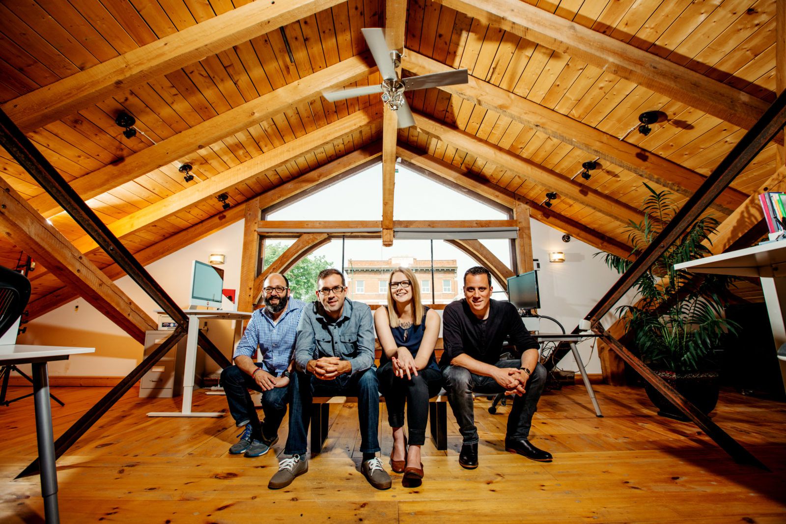 four people sitting and looking at the camera in a wood studio